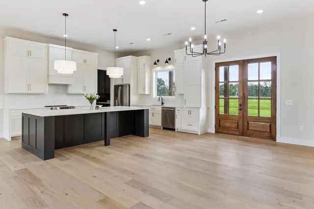 a large kitchen with stainless steel appliances granite countertop a stove top oven a refrigerator a sink and a fireplace with wooden floor