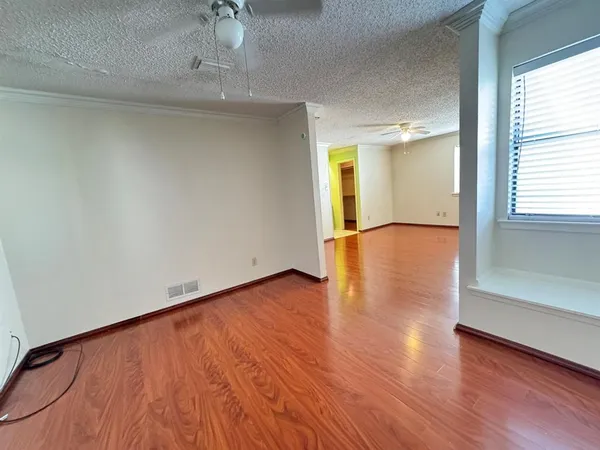 a view of empty room with wooden floor and fan
