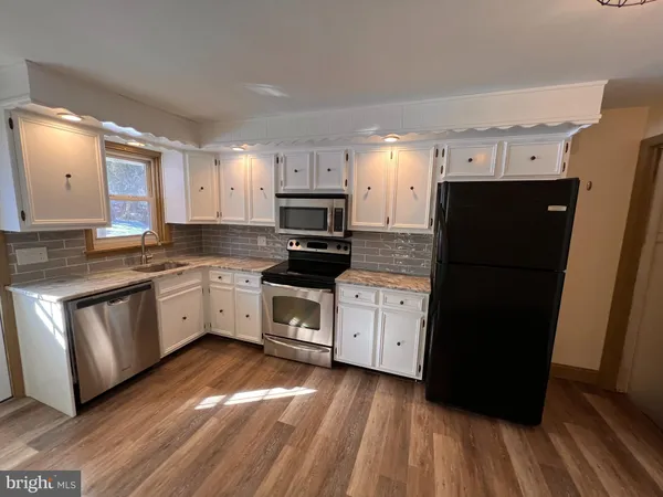 a kitchen with a refrigerator a stove top oven and wooden floor