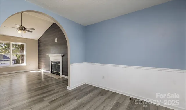 an empty room with wooden floor fireplace and windows