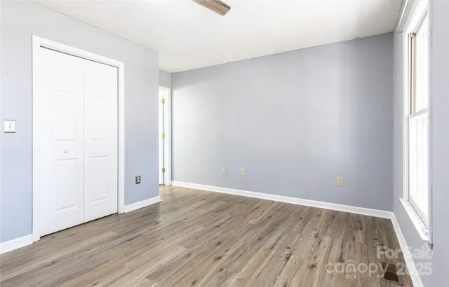 an empty room with wooden floor and windows