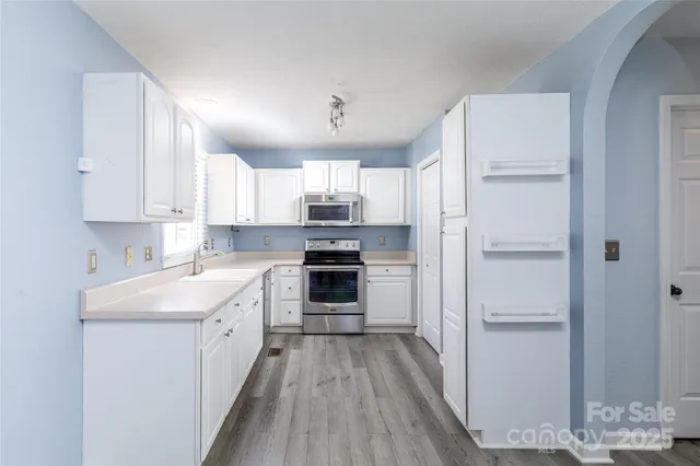 a kitchen with a refrigerator a sink and dishwasher with wooden floor