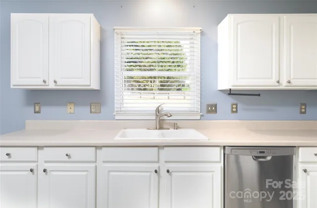 a kitchen with granite countertop white cabinets and a window