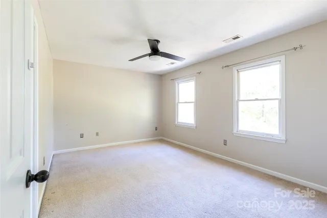 an empty room with windows and chandelier fan
