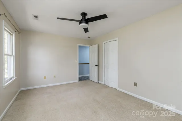 a view of an empty room with a chandelier fan