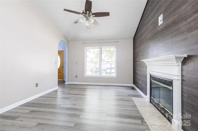 an empty room with wooden floor fan and windows
