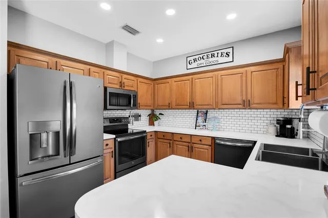 a kitchen with stainless steel appliances a sink stove refrigerator and cabinets