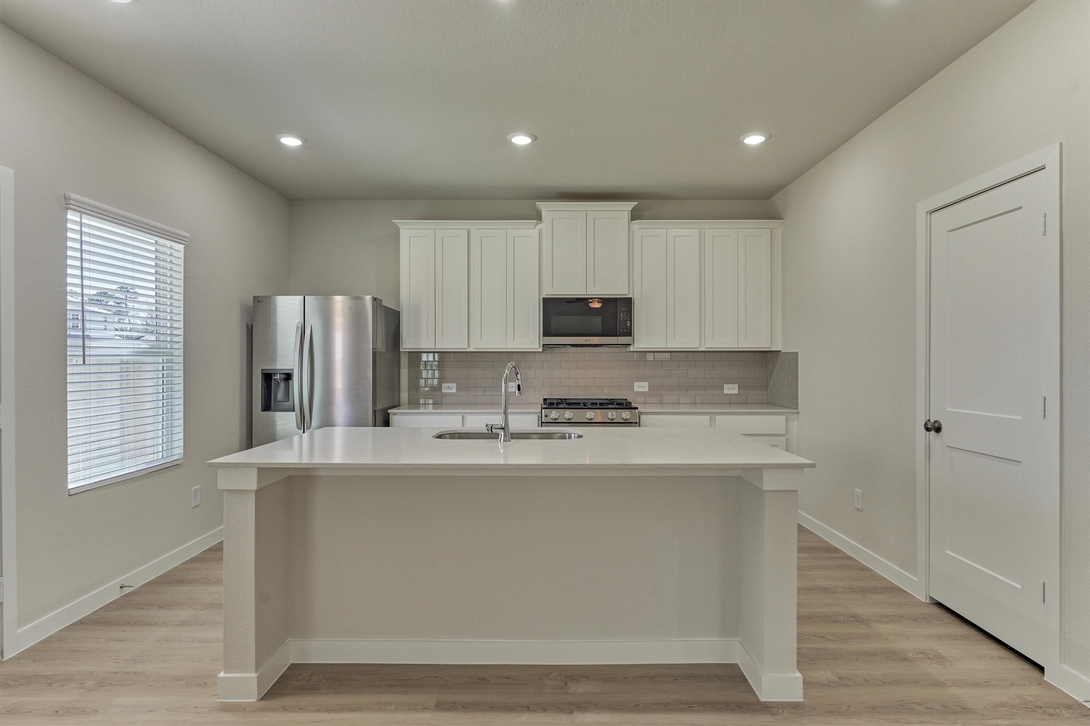 282 Brazen Forest Trail Magnolia, TX 77355 - Photo 14 of 36 a kitchen with stainless steel appliances granite countertop a refrigerator a stove a sink and white cabinets with wooden floor