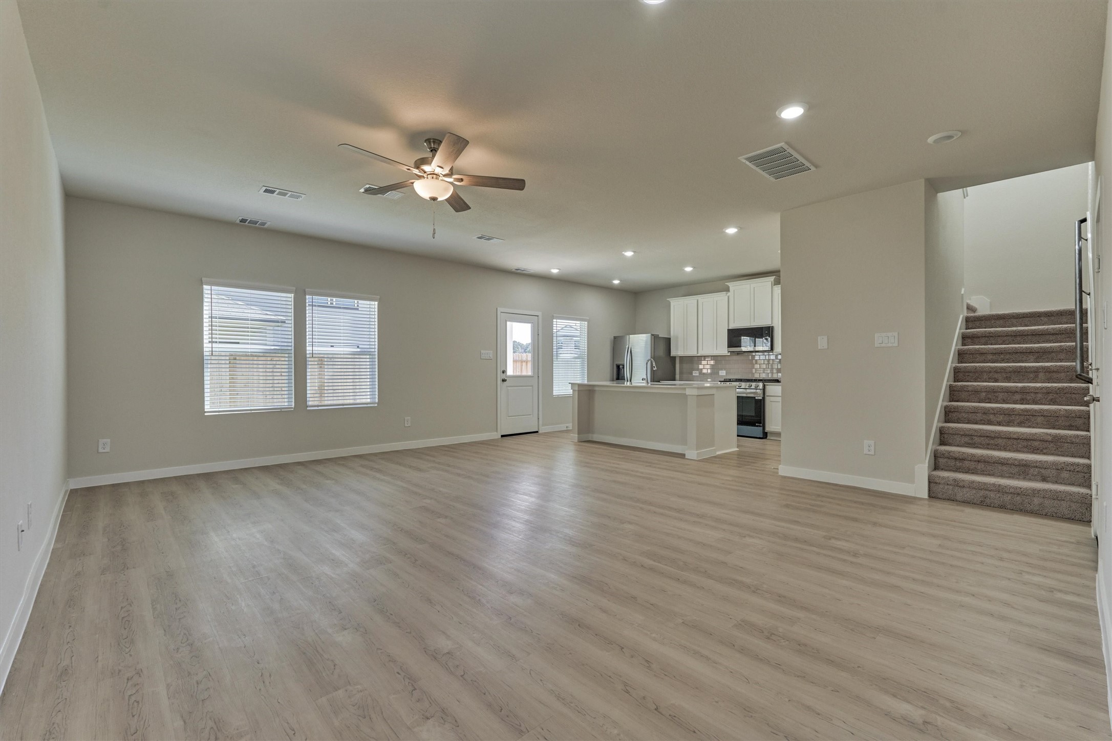 282 Brazen Forest Trail Magnolia, TX 77355 - Photo 9 of 36 a view of kitchen and empty room with wooden floor and windows