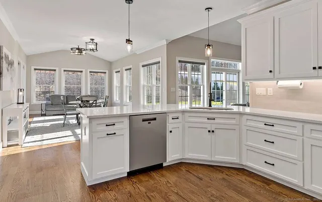 a large kitchen with cabinets a sink dishwasher a dining table and chairs with wooden floor