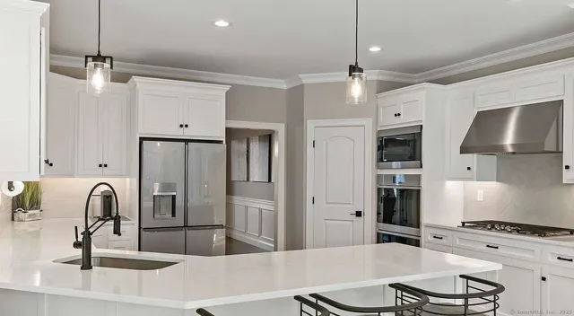 a kitchen with stainless steel appliances granite countertop a stove a refrigerator and a sink with wooden floor