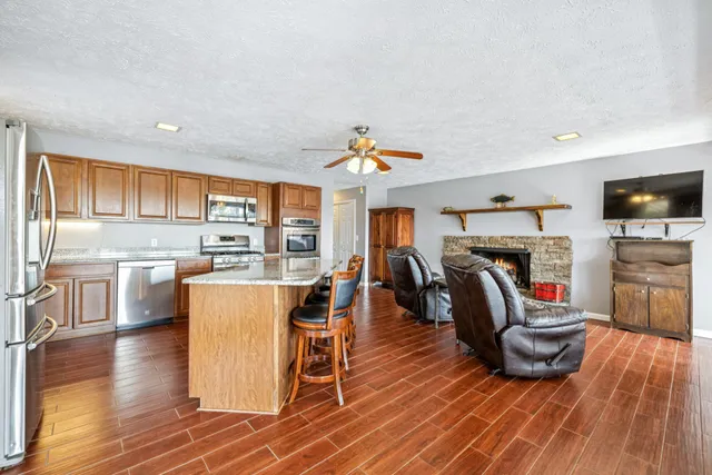 a kitchen with stainless steel appliances granite countertop a refrigerator sink and wooden cabinets