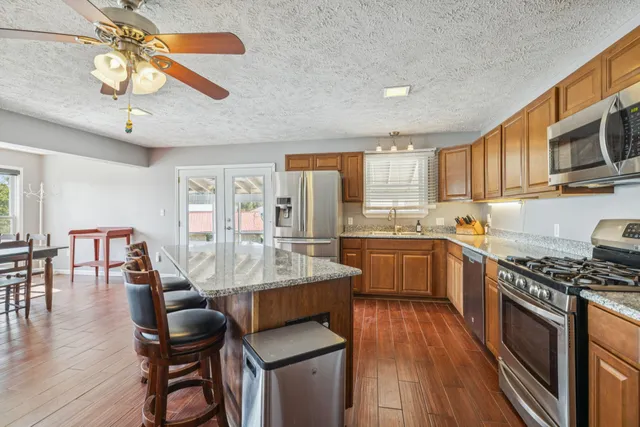 a kitchen with granite countertop a sink stove and refrigerator