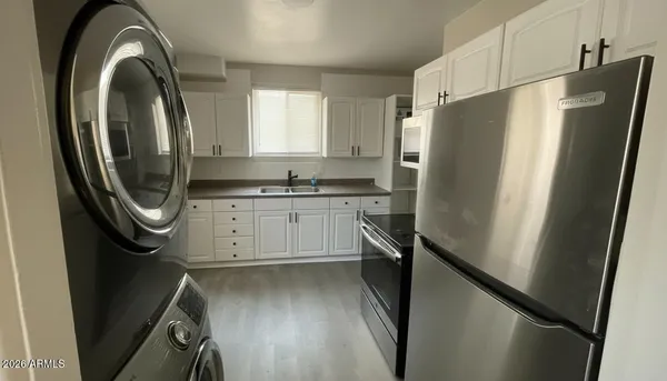 a kitchen with stainless steel appliances a refrigerator a sink a stove and white cabinets