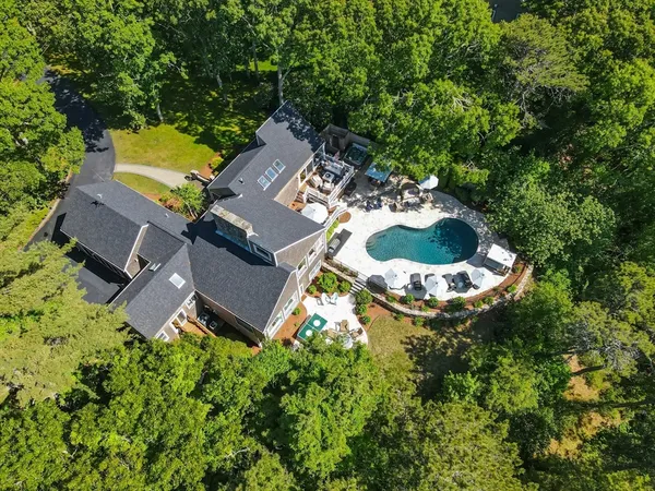 an aerial view of a residential houses with outdoor space and trees all around