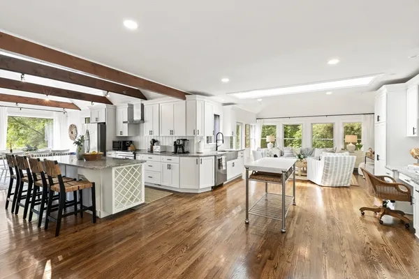 a living room with stainless steel appliances granite countertop furniture wooden floor and a rug
