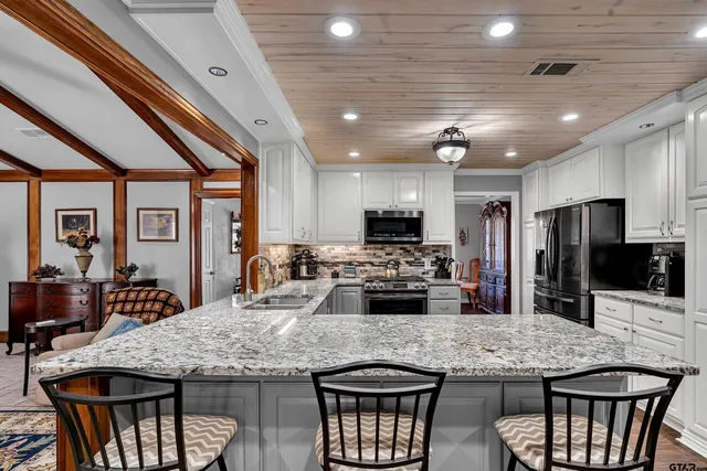 a kitchen with stainless steel appliances granite countertop a kitchen island and chairs in it