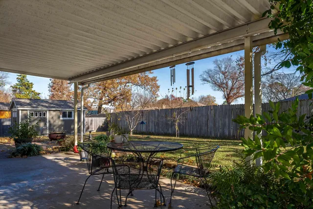 a view of a backyard with table and chairs potted plants and floor to ceiling window