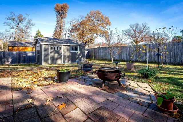 a view of a backyard with table and chairs couches under an umbrella with wooden fence