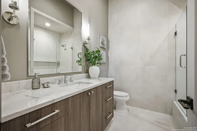 a bathroom with a granite countertop sink a toilet and mirror