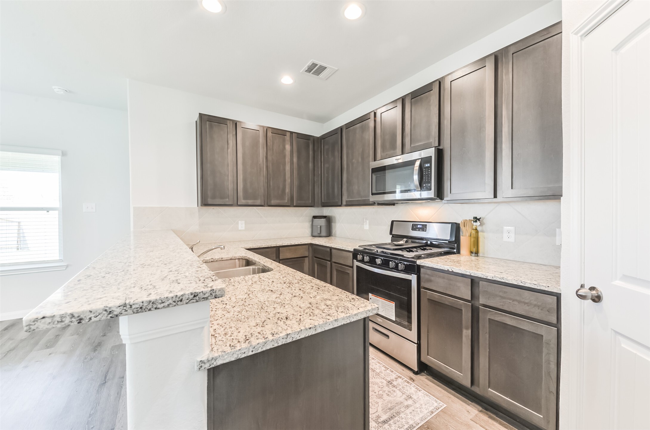 5522 Briana Dee Drive Rosharon, TX 77583 - Photo 13 of 37 a kitchen with stainless steel appliances granite countertop a stove top oven a sink dishwasher and wooden cabinets