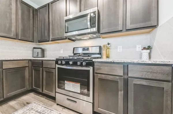 a kitchen with stainless steel appliances granite countertop a sink stove and microwave