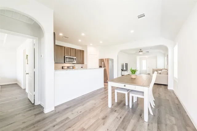 a living room with furniture a wooden floor and a kitchen view