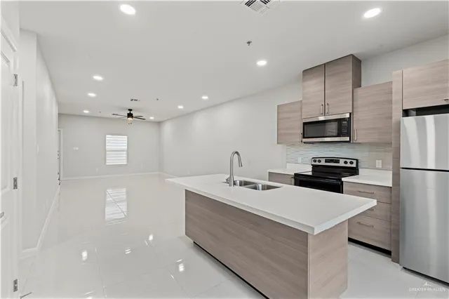 a kitchen with a sink a counter top space stainless steel appliances and cabinets