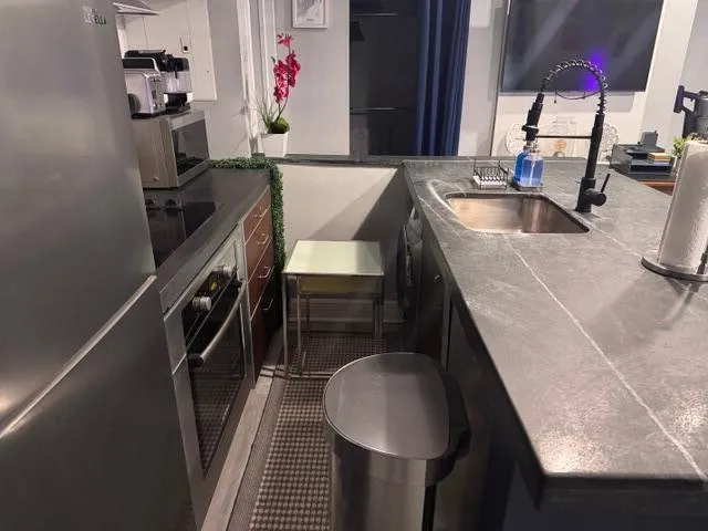 a kitchen with a sink and a stove with wooden floor
