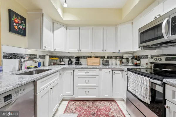 a kitchen with stainless steel appliances granite countertop a sink and dishwasher a stove top oven with white countertops