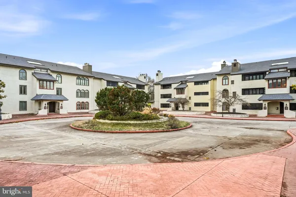 a view of a white building among the street with palm trees