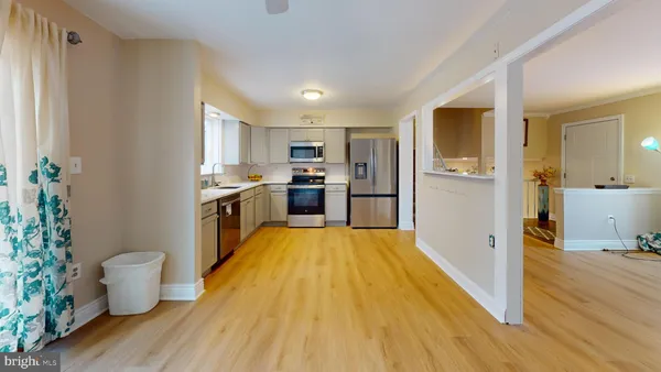 a large kitchen with a wooden floor and stainless steel appliances