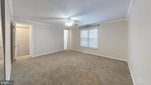 an empty room with windows and chandelier fan