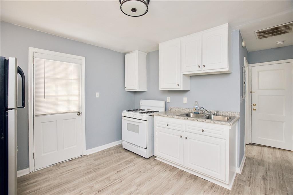 3323 Midway Road, Unit 1 Decatur, GA 30032 - Photo 3 of 10 a kitchen with stainless steel appliances white cabinets and wooden floors