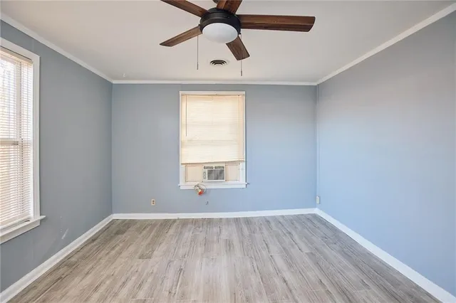 a view of empty room with wooden floor and fan