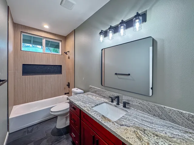 a bathroom with a granite countertop sink and a mirror