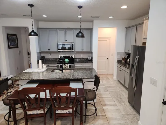 a kitchen with stainless steel appliances granite countertop a refrigerator a stove top oven a sink dishwasher and a refrigerator