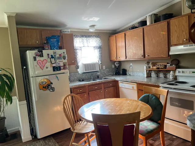 a kitchen with stainless steel appliances granite countertop a refrigerator a sink dishwasher a dining table and chairs with wooden floor