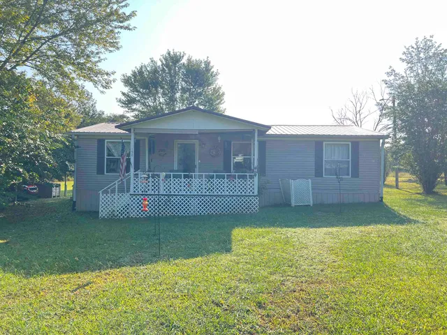 a view of a house with a yard and a large tree