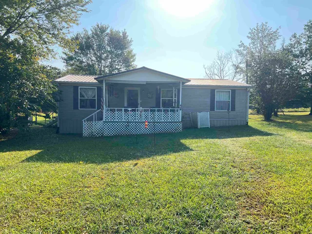 a view of a house with a yard and a large tree