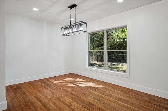 a view of empty room with wooden floor and window
