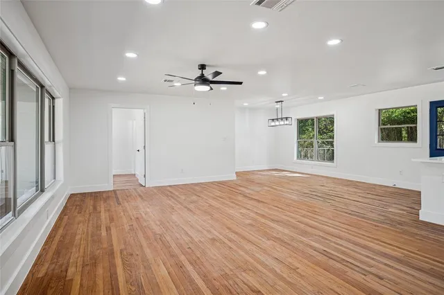 a view of an empty room with a window and wooden floor