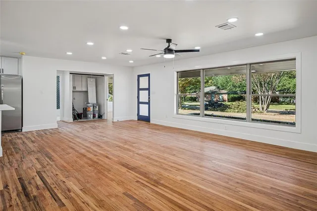 an empty room with wooden floor fan and windows