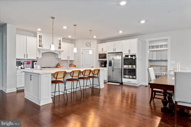 a open kitchen with stainless steel appliances granite countertop a stove a sink a refrigerator and white cabinets with wooden floor