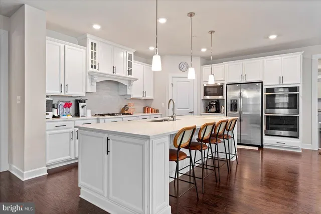 a kitchen with stainless steel appliances granite countertop a sink a stove a refrigerator and island with wooden floor