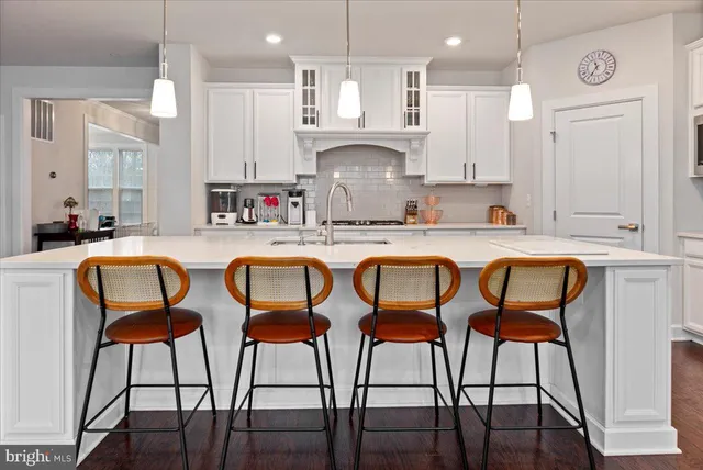 a kitchen with stainless steel appliances granite countertop a table chairs sink and wooden floor