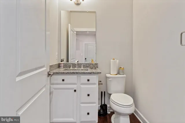 a bathroom with a granite countertop toilet sink and mirror