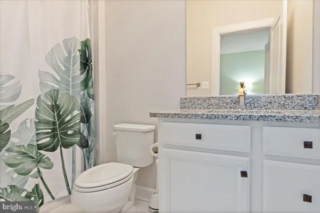 a bathroom with a granite countertop toilet and a sink