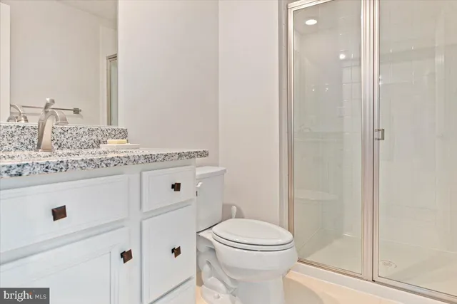 a bathroom with a granite countertop sink mirror vanity and toilet