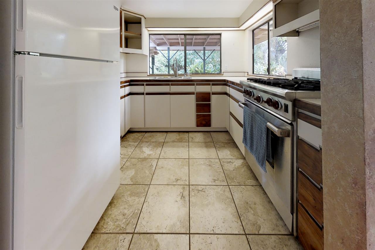 911 Kauhikoa Road Haiku, HI 96708 - Photo 7 of 30 a kitchen with a stove a refrigerator and a window
